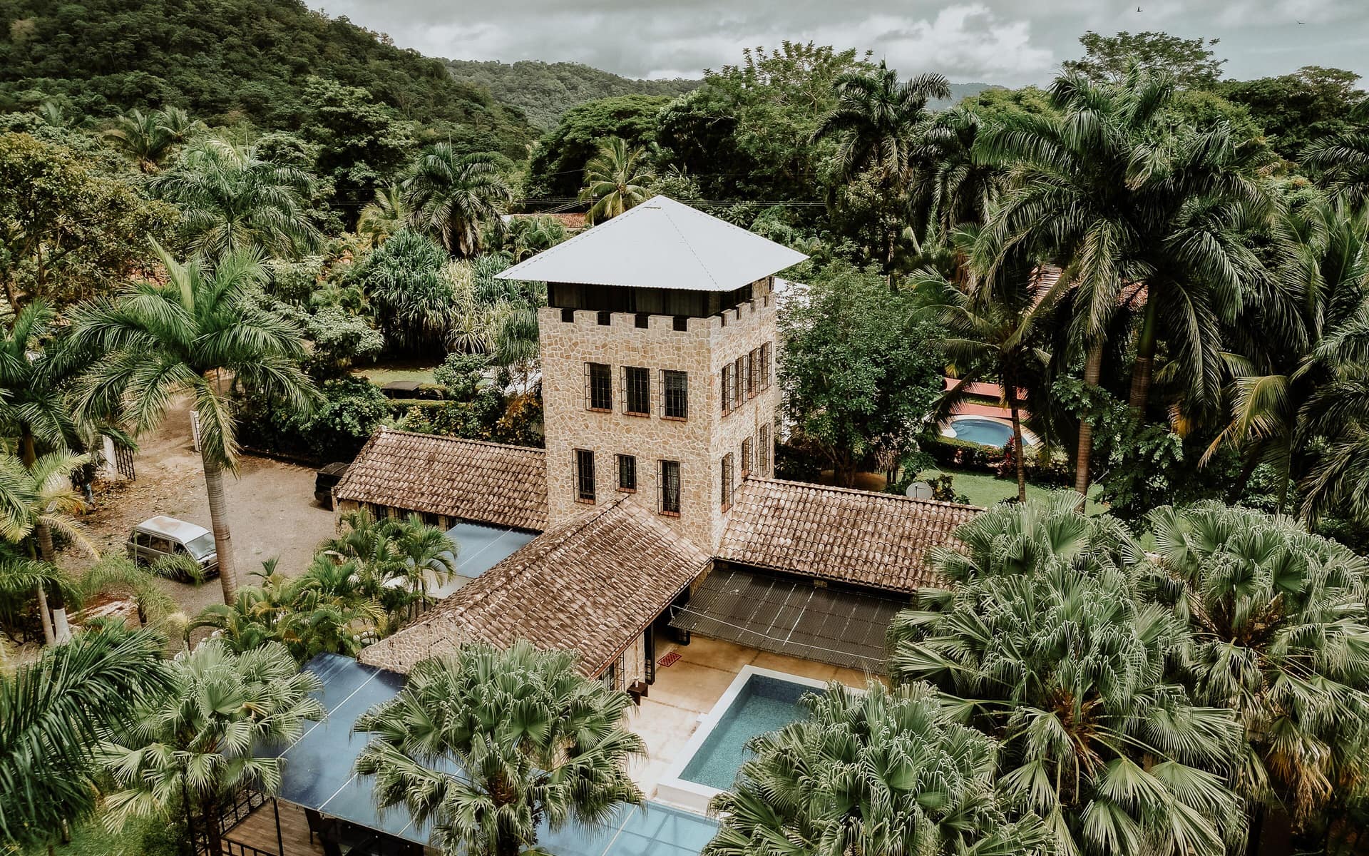Aerial view of Castillo's stone tower and pools surrounded by tropical forest.